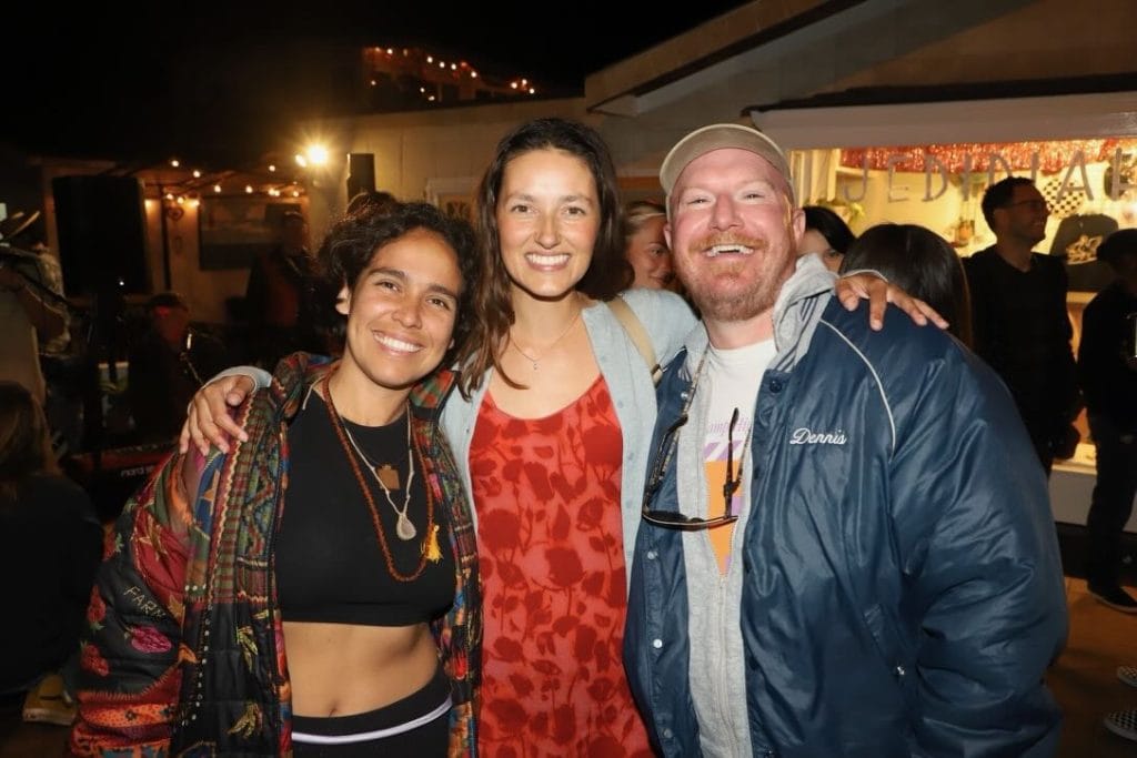 Two women and a man pose for a photo at a party