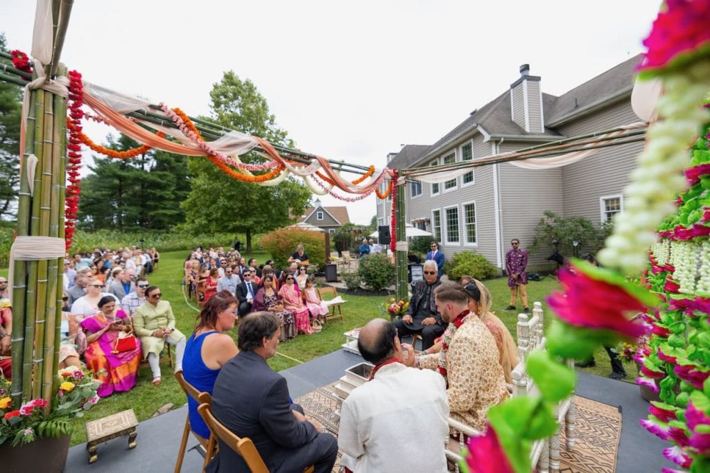 A priest is speaking at an outdoor Indian wedding ceremony