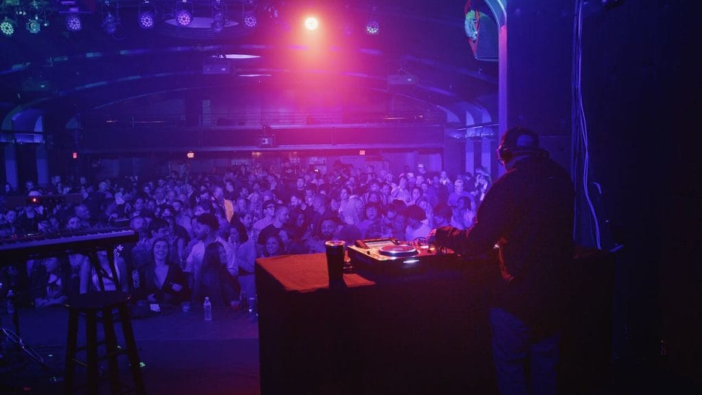 Large crowd in a ballroom with a DJ on stage