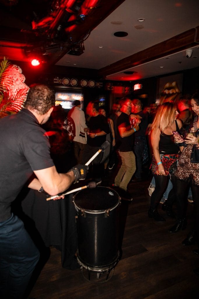 A drummer plays at a party with a DJ